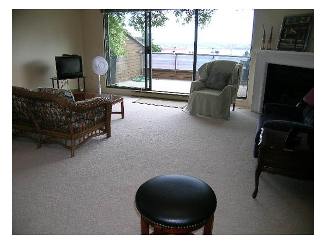 Furnished living room with large sliding glass doors, city view, and cozy seating. - 3-220 East 4th Street, North Vancouver