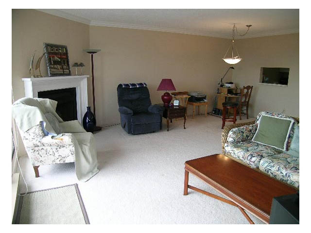 Furnished living room with white walls, a fireplace, and a wooden coffee table. - 3-220 East 4th Street, North Vancouver