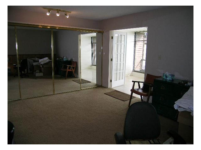 Living room with sliding glass doors leading to a patio, carpeted floor, and a desk with chair. - 3-220 East 4th Street, North Vancouver