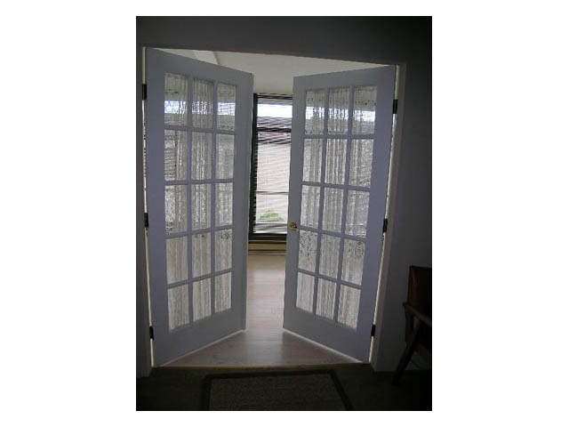 Bright entryway with French doors leading to a patio, showcasing a serene outdoor view. - 3-220 East 4th Street, North Vancouver