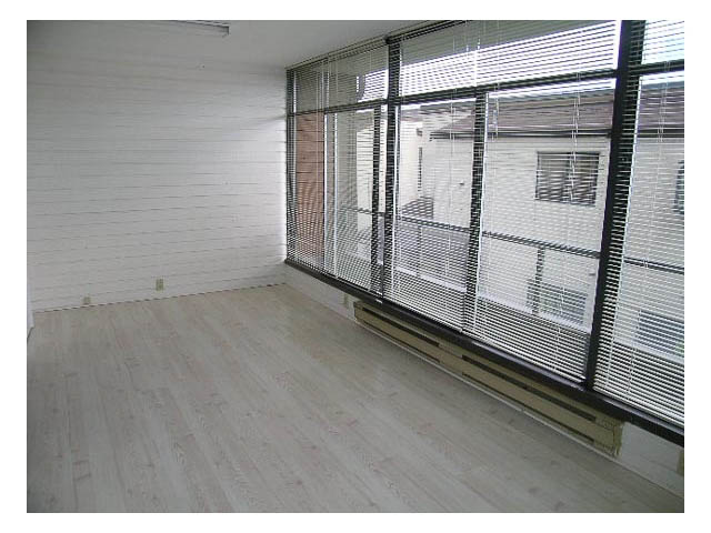 Bright living room with hardwood floors and large windows showing city view. - 3-220 East 4th Street, North Vancouver