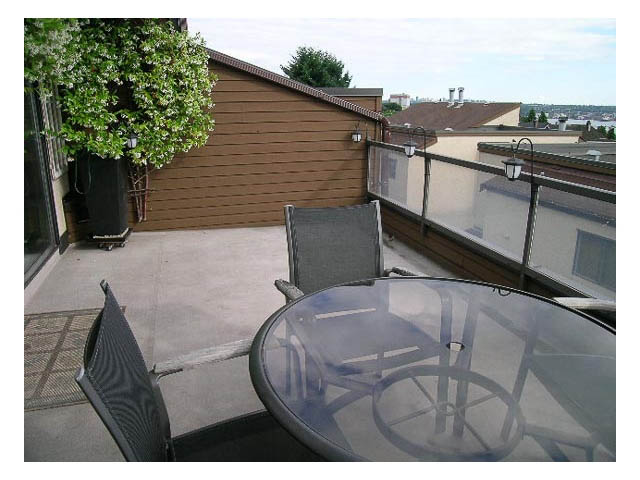 Furnished patio with glass table and chairs, city view in background. - 3-220 East 4th Street, North Vancouver