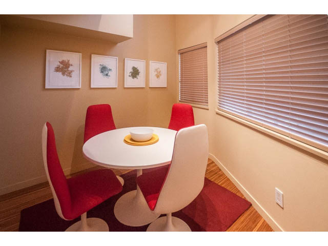 Bright dining area with red chairs, white table, and framed botanical art. - 1882 Whyte Avenue, Vancouver West Side