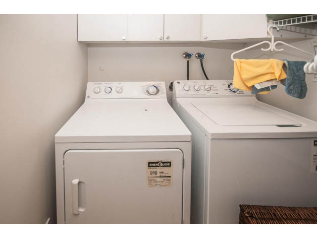 Laundry room with stacked washer and dryer, yellow towel hanging. - 1882 Whyte Avenue, Vancouver West Side