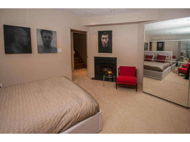Furnished bedroom with red furniture and large mirror reflecting living area. - 1882 Whyte Avenue, Vancouver West Side