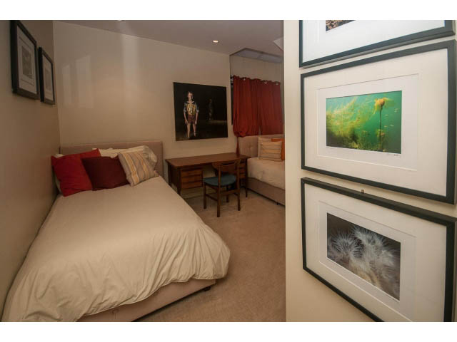 Furnished bedroom with a neatly made bed, framed artwork, and a cozy ambiance. - 1882 Whyte Avenue, Vancouver West Side