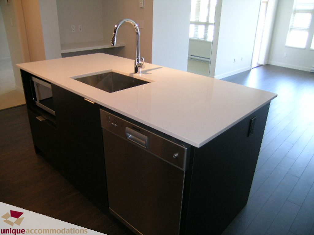 Bright kitchen with white countertops, dark cabinets, and hardwood floors. - 510 - 1677 Lloyd Avenue, North Vancouver