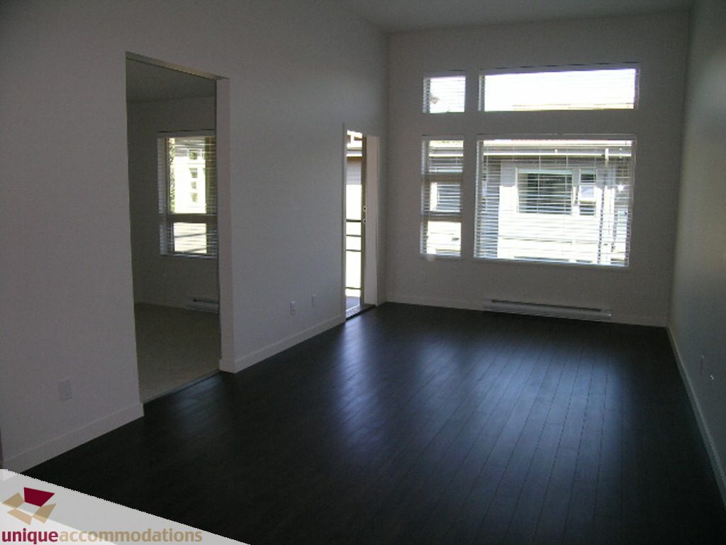 Bright living room with hardwood floors and large windows. - 510 - 1677 Lloyd Avenue, North Vancouver