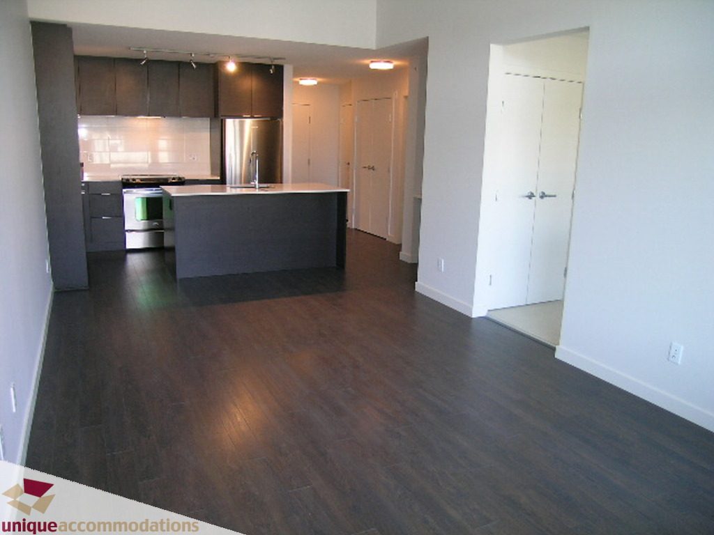 Bright kitchen with dark countertops and hardwood floors, leading to a spacious living area. - 510 - 1677 Lloyd Avenue, North Vancouver