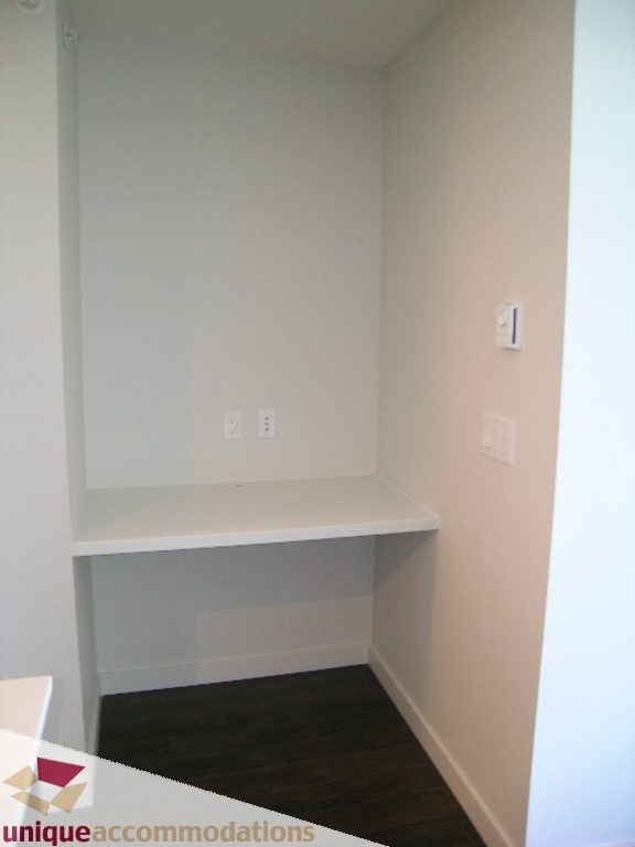 Compact corner desk with built-in shelving and outlets, dark hardwood floors. - 510 - 1677 Lloyd Avenue, North Vancouver