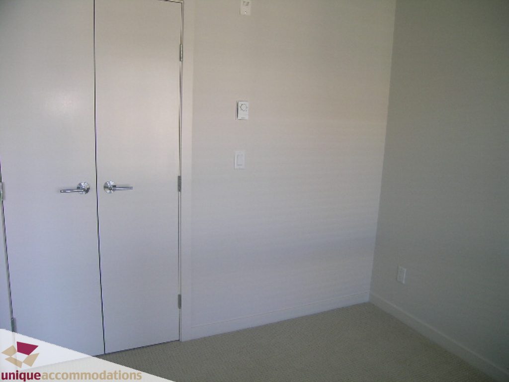Bright living room with white walls and carpeted floor. - 510 - 1677 Lloyd Avenue, North Vancouver
