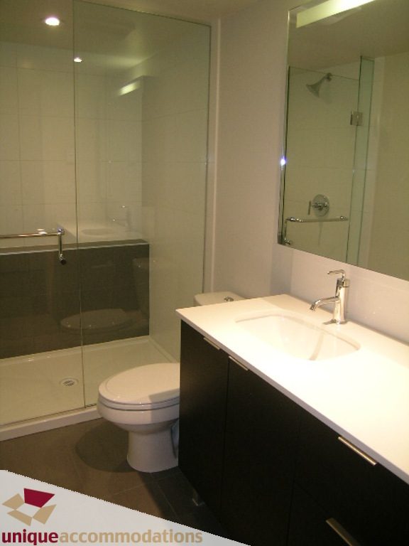 Modern bathroom with sleek white countertop and dark cabinetry. - 510 - 1677 Lloyd Avenue, North Vancouver