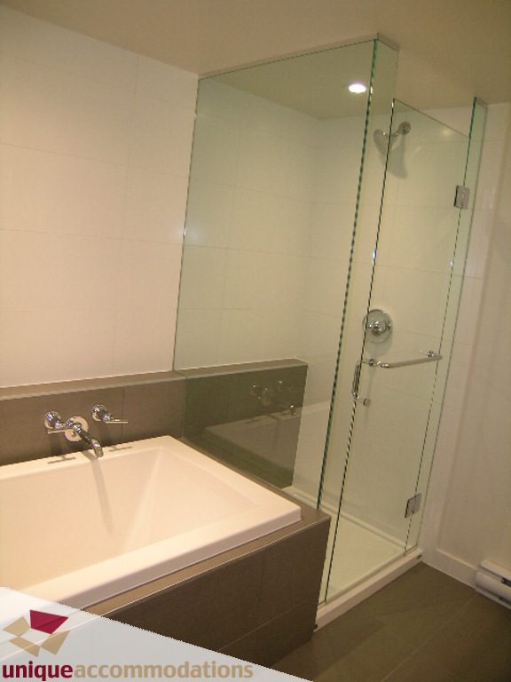 Furnished bathroom with modern bathtub and glass shower enclosure. - 510 - 1677 Lloyd Avenue, North Vancouver