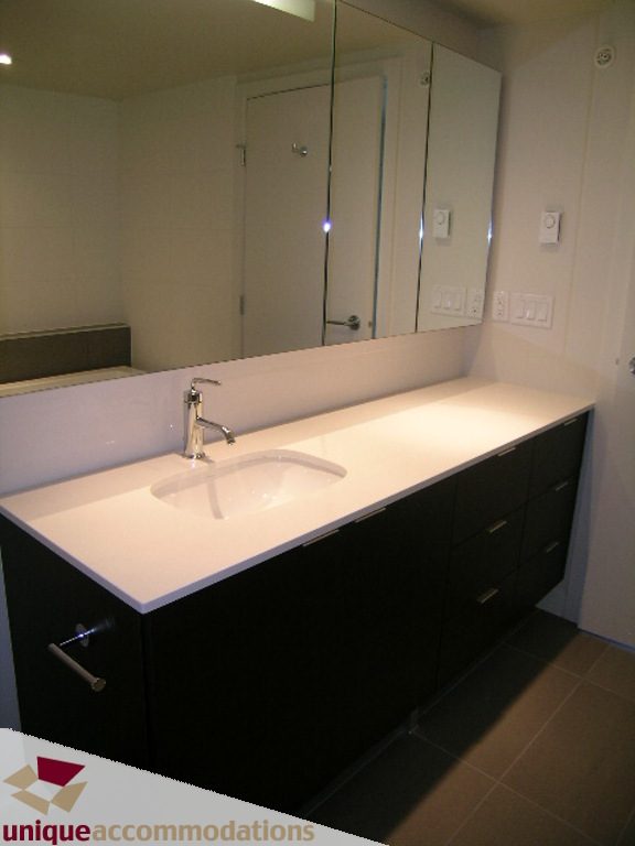 Furnished bathroom with modern sink, black cabinets, and large mirror. - 510 - 1677 Lloyd Avenue, North Vancouver