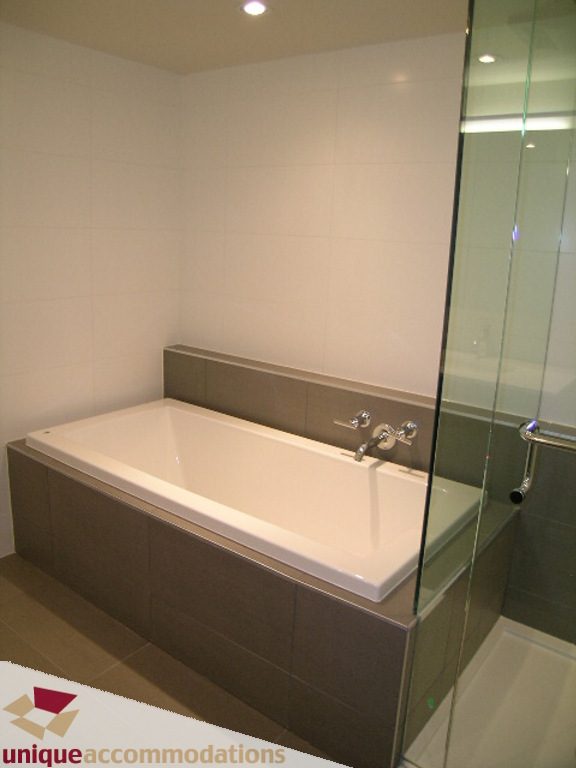 Modern bathroom with a sleek bathtub and glass shower enclosure. - 510 - 1677 Lloyd Avenue, North Vancouver