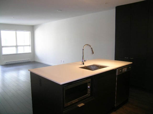 Bright kitchen with white countertops, black cabinets, and hardwood floors. - 302 - 1677 Lloyd Avenue, North Vancouver