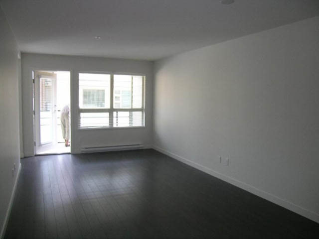 Spacious living room with hardwood floors and large windows. - 302 - 1677 Lloyd Avenue, North Vancouver