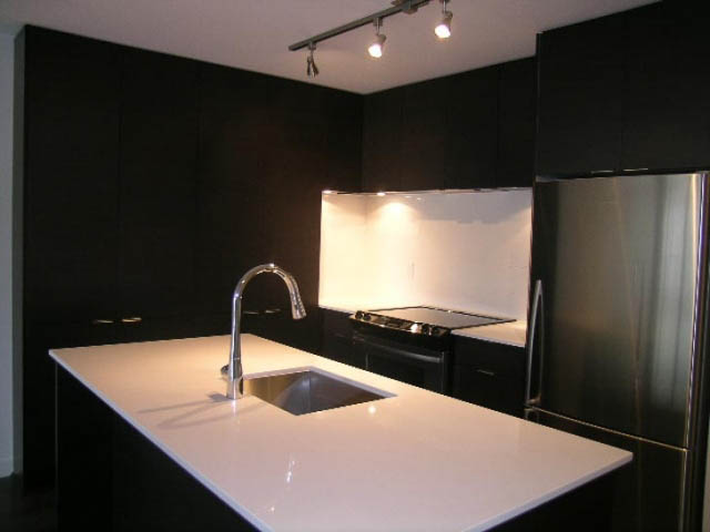 Bright kitchen with black cabinetry, white countertops, and stainless steel appliances. - 302 - 1677 Lloyd Avenue, North Vancouver