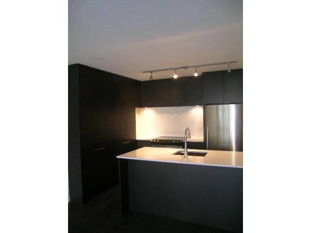 Bright kitchen with black cabinets, stainless steel appliances, and track lighting. - 302 - 1677 Lloyd Avenue, North Vancouver