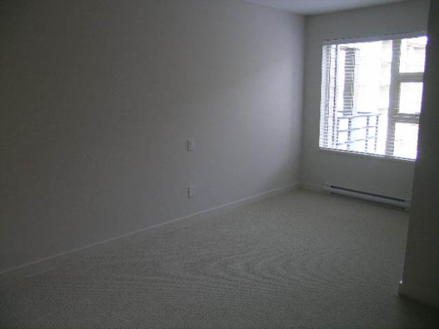 Bright and airy bedroom with carpeted floors and a large window. - 302 - 1677 Lloyd Avenue, North Vancouver