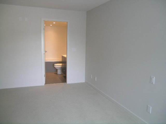 Bright living room with carpeted floor and view into bathroom. - 302 - 1677 Lloyd Avenue, North Vancouver