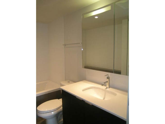 Modern bathroom with sleek countertop and large mirror. - 302 - 1677 Lloyd Avenue, North Vancouver