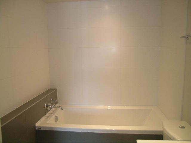 Bathroom with white bathtub and tiled walls. - 302 - 1677 Lloyd Avenue, North Vancouver