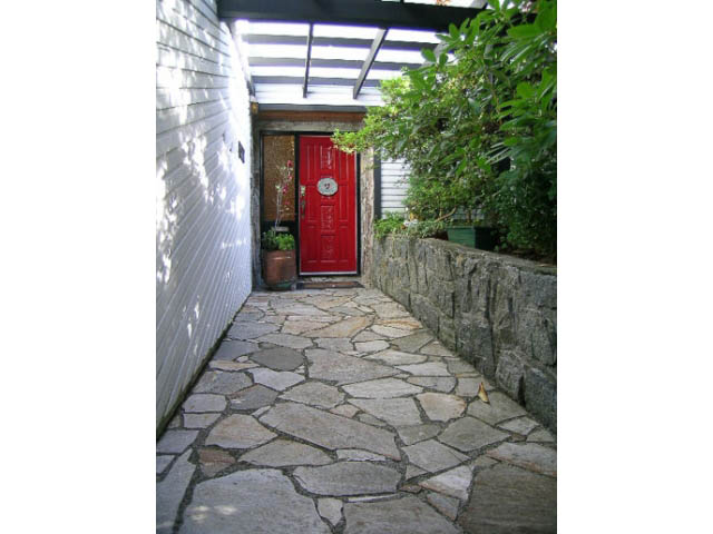Entryway with stone pathway leading to a red door, surrounded by greenery. - 1077 Blue Grouse Way, North Vancouver