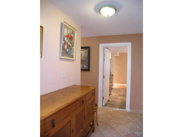 Furnished living room with wooden cabinets and tiled floor leading to another room. - 1077 Blue Grouse Way, North Vancouver