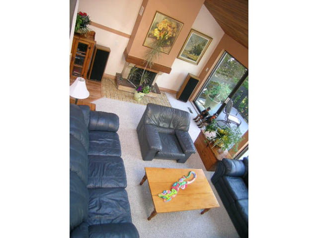 Spacious living room with leather furniture, fireplace, and large windows. - 1077 Blue Grouse Way, North Vancouver