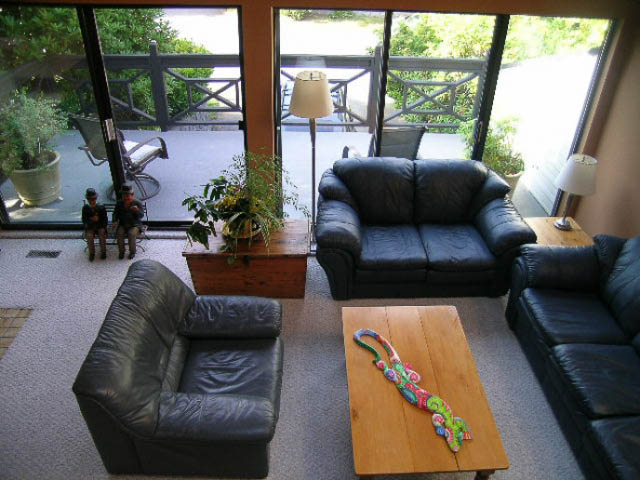 Spacious living room with large windows, leather furniture, and outdoor patio access. - 1077 Blue Grouse Way, North Vancouver