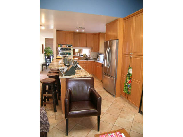 Bright kitchen with wooden cabinets, stainless steel appliances, and tiled floor. - 1077 Blue Grouse Way, North Vancouver
