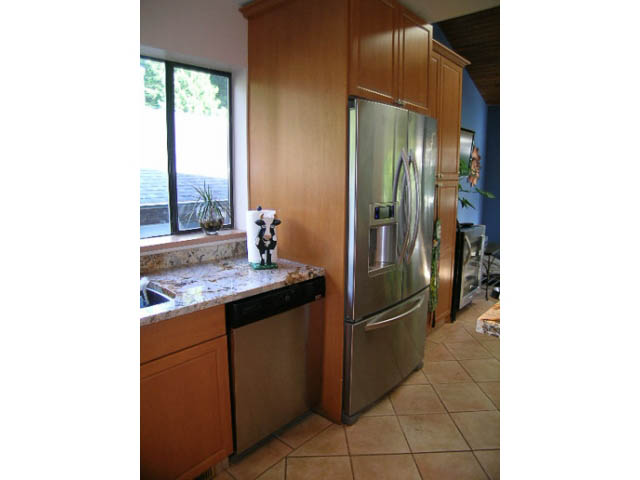 Bright kitchen with stainless steel appliances, wooden cabinets, and a city view. - 1077 Blue Grouse Way, North Vancouver