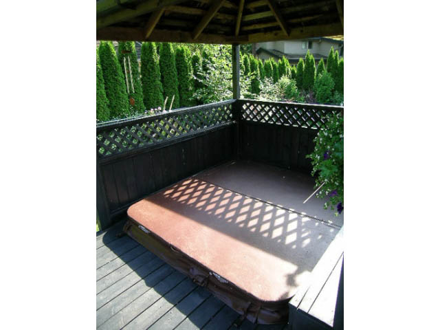 Furnished deck with wooden bench and lattice railing, surrounded by greenery. - 1077 Blue Grouse Way, North Vancouver