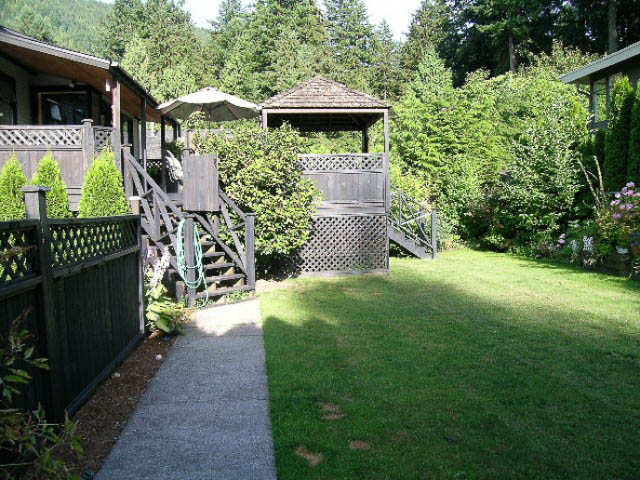Fenced backyard with gazebo, grassy area, and lush greenery. - 1077 Blue Grouse Way, North Vancouver