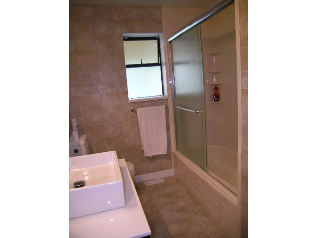 Bathroom with beige tiles, glass shower, and white sink. - 1077 Blue Grouse Way, North Vancouver