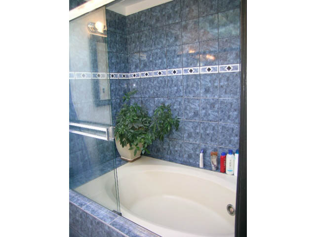 Bathroom with blue tiles and a white bathtub, modern design. - 1077 Blue Grouse Way, North Vancouver