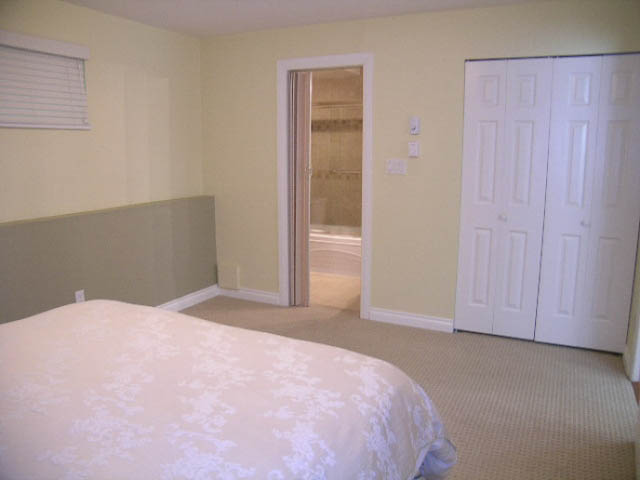 Spacious bedroom with a large bed, closet, and built-in bench. - 1077 Blue Grouse Way, North Vancouver