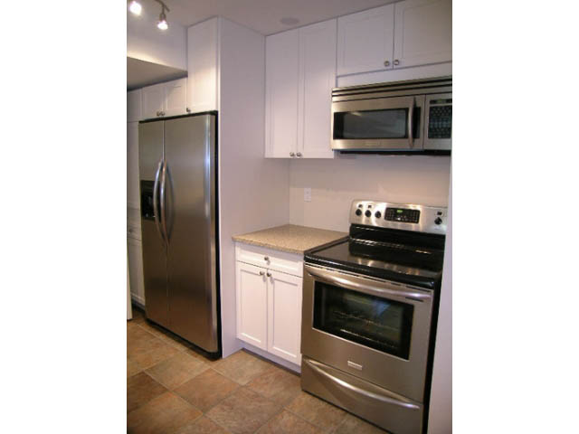Bright kitchen with stainless steel appliances, granite countertops, and white cabinets. - 1077 Blue Grouse Way, North Vancouver