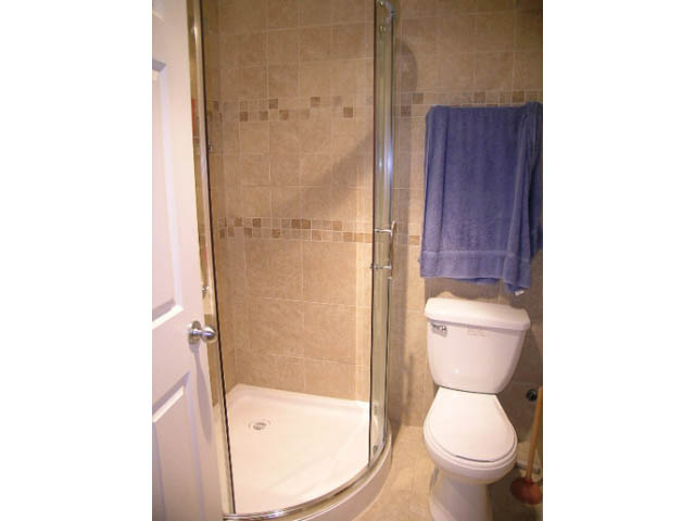 Bathroom with corner shower, beige tiles, and purple towel. - 1077 Blue Grouse Way, North Vancouver