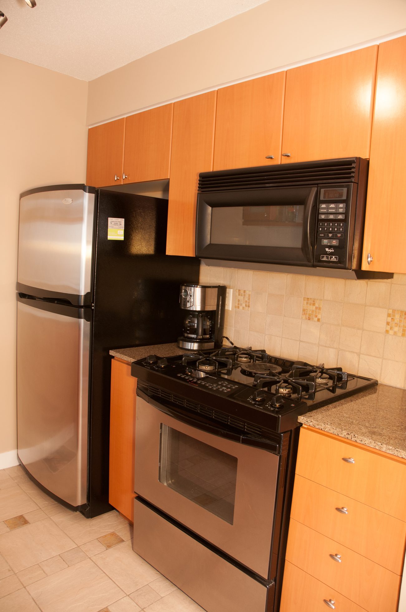 Bright kitchen with granite countertops, stainless steel appliances, and wooden cabinets. - 1708 - 1438 Richards Street, Vancouver Downtown