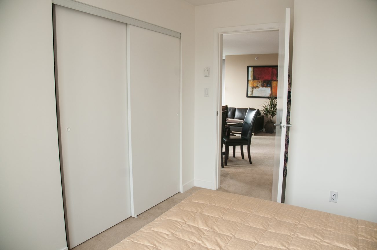 Furnished bedroom with sliding closet doors and a view into the dining area. - 1708 - 1438 Richards Street, Vancouver Downtown
