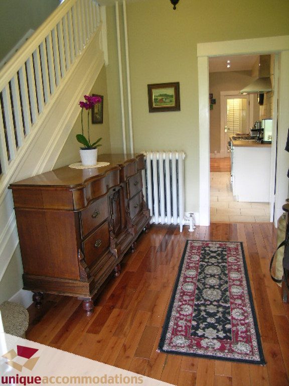 Foyer with wooden floors, ornate dresser, and kitchen in the background. - 813 - 5th Street East, North Vancouver