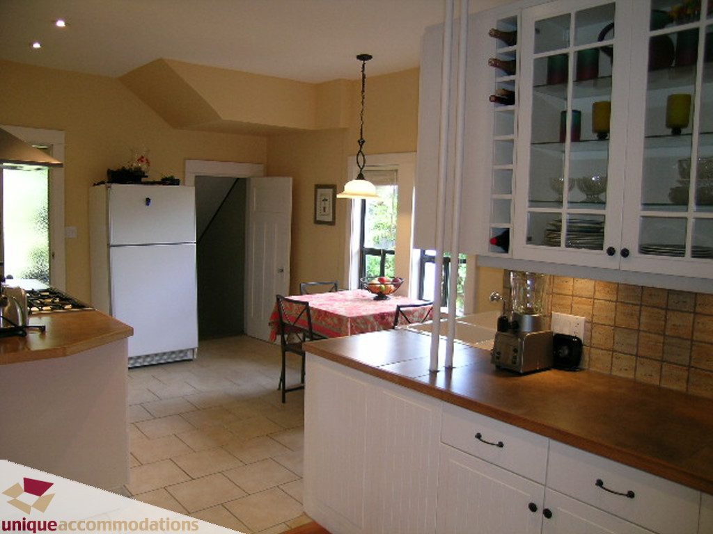 Bright kitchen with white cabinets, wooden countertops, and a view of the dining area. - 813 - 5th Street East, North Vancouver