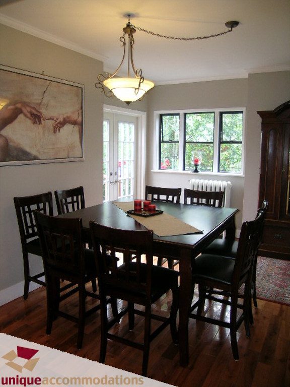 Dining room with dark wood table, chairs, and a large window with a view of greenery. - 813 - 5th Street East, North Vancouver