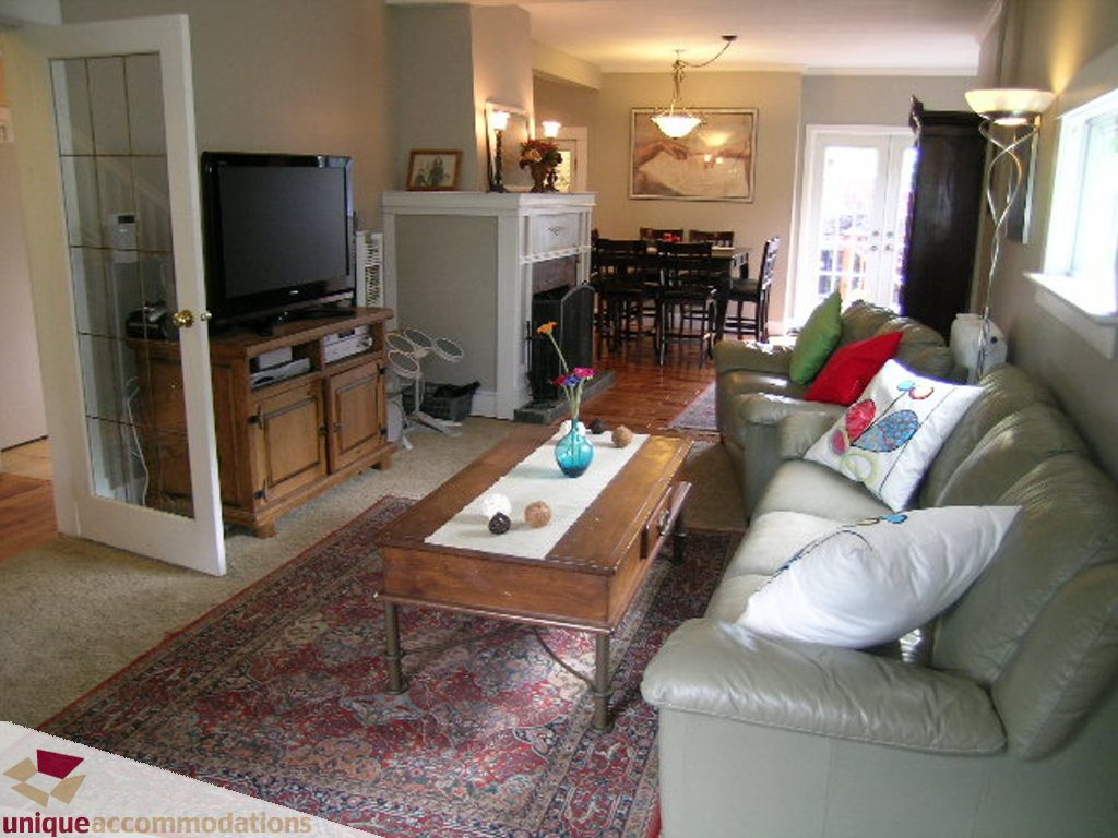 Furnished living room with leather couch, wooden coffee table, and Persian rug. - 813 - 5th Street East, North Vancouver