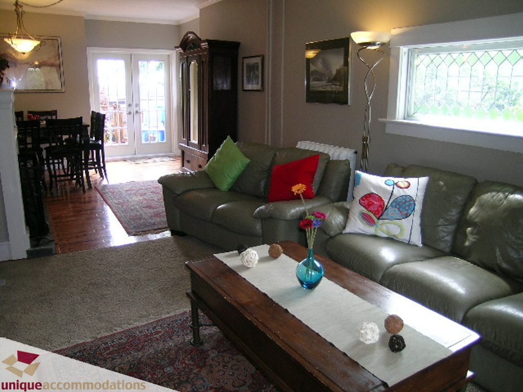 Furnished living room with leather couches, hardwood floors, and a wooden coffee table. - 813 - 5th Street East, North Vancouver