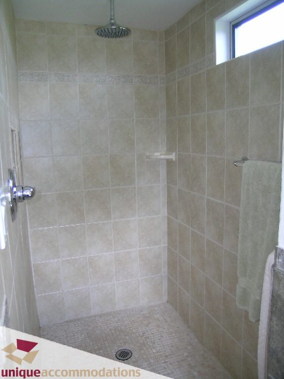 Bright shower with beige tiles and a rain shower head. - 813 - 5th Street East, North Vancouver