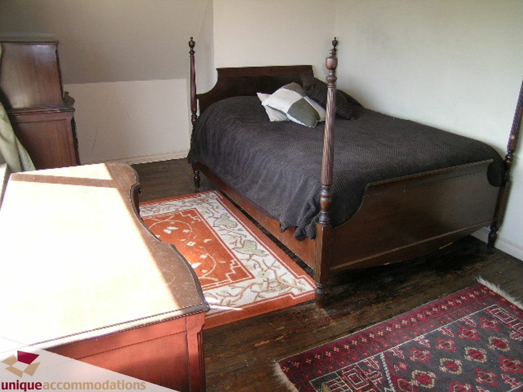Spacious bedroom with dark wood furniture and patterned rugs. - 813 - 5th Street East, North Vancouver