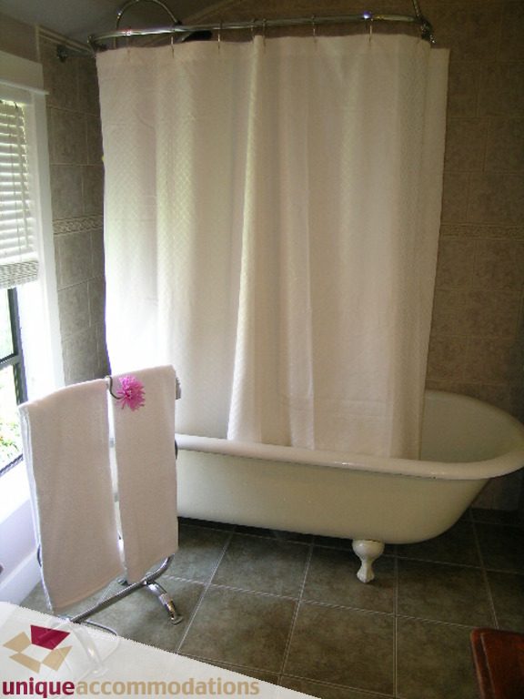 Bright bathroom with clawfoot tub and white shower curtain. - 813 - 5th Street East, North Vancouver